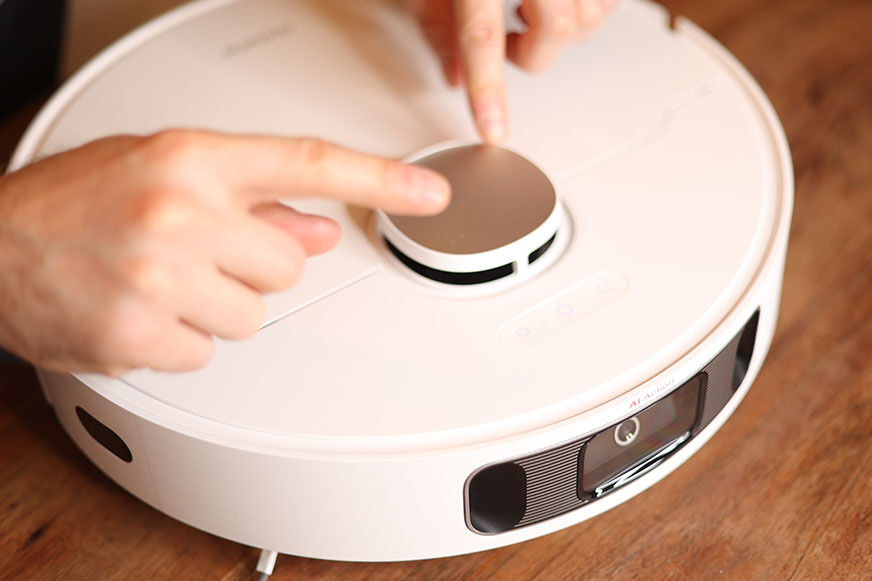 Der Lasernavigationsturm des Dreame L10s Ultra wird mit beiden Händen berührt.